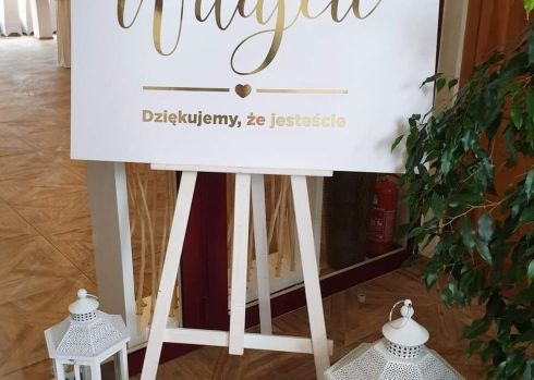 Tablica powitalna ze złotym napisem